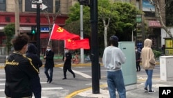 上海静安区居民排队做新冠病毒核酸检测,路上有人打着中共与中国的旗帜走过。(2022年4月1日)