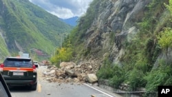 中国西南部四川省甘孜州泸定县当地时间星期一(2022年9月5日)下午发生6.8级地震。新华社发布的照片显示地震造成山体滑坡,巨石滚落,车辆通行受阻。-美联社/新华社照。