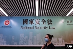 行人走过香港街头港版国安法的宣传牌。(2020年7月28日)