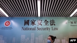 行人走过香港街头港版国安法的宣传牌。(2020年7月28日)