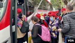 大批戴上旅行团鲜红色鸭舌帽的中国大陆旅客,吃完中饭后登上旅游巴离开土瓜湾 (美国之音/汤惠芸)