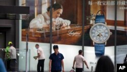 北京街头的行人走过一家商场悬挂的瑞士奢侈品品牌手表宝珀都的广告。(2023年6月13日)