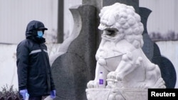 资料照:疫情期间上海黄浦江边的一座石狮子和一名保安。(路透社)