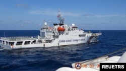 资料照片:2024年2月8日,菲律宾南中国海的斯卡伯勒浅滩(中国称黄岩岛)附近,一艘中国海警船从菲律宾海警船“特雷莎·马格巴努亚号”旁驶过。(路透社照片)