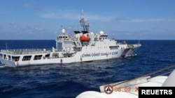 资料照:2024年2月8日,菲律宾南中国海斯卡伯勒浅滩附近,一艘中国海岸警卫队船只在菲律宾海岸警卫队船只特雷莎·马格巴努亚号旁驶过。(路透社)