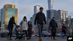 资料照片:行人穿过北京中心商务区办公楼附近的交通路口。(2024年2月8日)