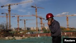 资料照:一名打手机的工人走过北京的一处建筑工地。(2022年4月14日)
