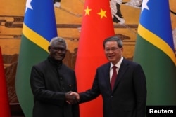 中国总理李强与所罗门群岛总理索加瓦雷在一个签字仪式后握手。(2023年7月10日)