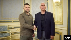 Ukrainian President Zelensky (L) and former US Vice President Mike Pence shake hands prior to their meeting. (Photo by Handout / AFP)