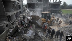 2024年2月23日,以色列空袭加沙地带代尔巴拉亚基家族的一栋住宅楼后,巴勒斯坦人在废墟中寻找幸存者。(美联社照片)