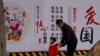 一名男子带着小女孩走过北京街头一面中国政府的宣传社会主义核心价值观的宣传墙。(2021年3月7日)