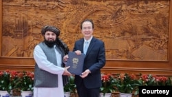 在塔利班提供的这张照片中,新任命的塔利班大使卡里米2023年12月1日在北京向中国外交部礼宾司司长洪磊递交国书副本。