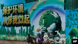 资料照:一名工人在北京的一面"保护环境从你我做起"的宣传画前休息。(2017年6月5日)