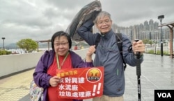将军澳反填海游行纠察赵小姐,与手持报纸挡雨、年约70岁的将军澳居民林和平 (美国之音/汤惠芸)