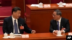 资料照片:中国国家主席习近平2023年3月12日在全国人民代表大会上与中国总理李强交谈。