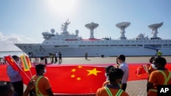 资料照:斯里兰卡港口工人在中国一带一路项目汉班托塔港手持中国国旗欢迎一艘装载着检测设备的中国考察船到港。(2022年8月16日)