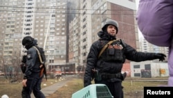 在基辅,一名警察帮助民众离开被俄军导弹破坏的居民楼。(2024年2月7日)