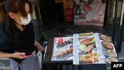在北京,日本驻华大使馆附近的一家日本餐馆前一名女子在看餐馆菜单。(2023年8月29日)