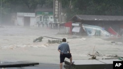 资料照:北京郊区妙峰山一名居民眼看着洪水淹没街道。(2023年8月1日)
