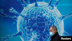 一名男子走过英国一家研究生物病毒的科研中心外的广告墙。(2020年8月3日)