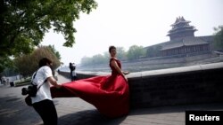 一名摄影师在北京故宫角楼外为一名红衣女子拍摄婚纱照。(2020年5月1日)