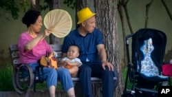 资料照片:北京公园里一对老夫妇和一名幼儿在乘凉。(2023年6月29日)