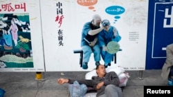 资料照:一名农民工在北京火车站的一个中国梦的政府宣传牌下打盹。