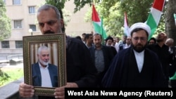 巴勒斯坦激进组织哈马斯领导人伊斯梅尔·哈尼亚( Ismail Haniyeh)遇袭身亡后,一名伊朗男子在德黑兰手持他的像片。(2024年7月31日)