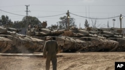 2024年4月11日,以色列士兵在以色列南部加沙地带边境附近的一个集结地修理坦克。