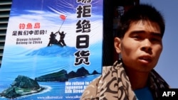 资料照:一名男子走过北京秀水街头一幅“拒绝日货”的宣传牌。(2012年9月17日)