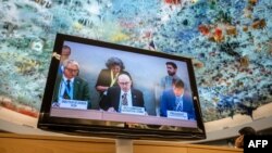 U.N. High Commissioner for Human Rights Volker Turk, center, is seen on a TV monitor speaking during a session of the 52nd U.N. Human Rights Council, in Geneva, on March 6, 2023.