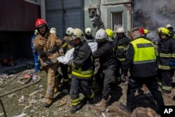 俄军袭击乌克兰乌曼市的居民楼后,乌克兰消防队员从楼房废墟中抬出死难者。(2023年4月28日)