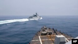 资料照片:美国海军发布的视频截图显示一艘中国军舰在台湾海峡从美国“钟云”号驱逐舰前方越过。(2023年6月3日)