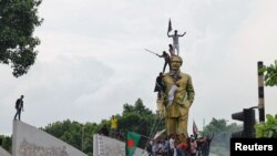 ဘင်္ဂလားဒေ့ရှ်ဝန်ကြီးချုပ် နုတ်ထွက်ရေးတောင်းဆိုသူတွေက ဒက္ကာမြို့မှာရှိတဲ့ နိုင်ငံ့ဖခင်ကြီး Sheikh Mujibur Rahman ရဲ့ရုပ်တုပေါ်တက်ပြီး ဖျက်စီးနေကြပုံ။ (သြဂုတ် ၅၊ ၂၀၂၄)