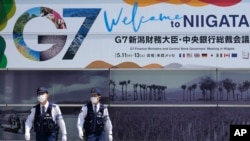 日本警察巡逻走过新泻街头张贴的七国集团财长会议宣传画。(2023年5月10日)