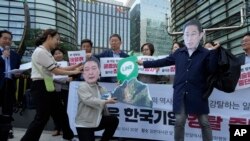 资料照片:韩国首尔的抗议者戴着印有日本首相岸田文雄和韩国总统尹锡悦头像的面罩,手拿着显示Line应用程序的标牌。(2024年5月14日)