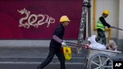 工人推着小车路过上海一家正在修建的商店。(2023年11月25日)