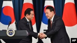 韩国总统尹锡悦(右)与日本首相岸田文雄在首尔总统府会晤后举行的联合记者会上握手。(2023年5月7日)