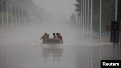 中国河北涿州民众在滔滔洪水中乘坐橡皮艇逃生。(2023年8月3日)