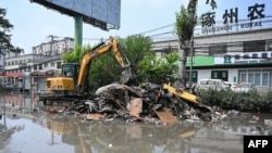 中国河北省涿州工人在清理遭洪水淹没的街道。(2023年8月9日)