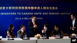 资料照:北京的一名移民咨询人员在一个记者会上与参会者交谈。(2014年3月4日)