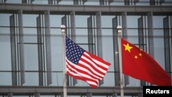 资料照片:中国北京,中美两国国旗在一家美国公司大楼外飘扬。(2021年1月21日,路透社)