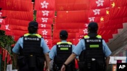 香港警察在香港主权移交中国27年纪念日走过挂满中国国旗和香港旗帜的街道。(2024年7月1日)