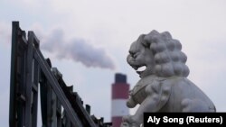 资料照 - 透过一座威严 的石狮雕像,可以看到上海附近的一座火力发电厂冒出的滚滚浓烟。照片来自路透社,拍摄时间是2021年10月21日。