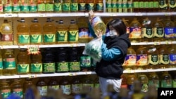 资料照:中国辽宁省沈阳市一家超市里,一名顾客在购买食用油。(2022年10月9日)