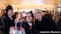 苹果公司首席执行官库克在上海出席第二家专卖店开张活动时与一名顾客合影。(2024年3月21日)