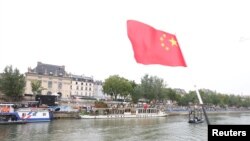 2024年7月26日巴黎奥运会开幕式上,一名中国代表队成员在塞纳河上挥动中国国旗。