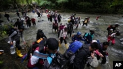 FILE - Migrants, mostly Venezuelans, cross a river during their journey through the Darien Gap from Colombia into Panama, hoping to reach the US, Oct. 15, 2022.