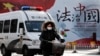 资料照:一辆警车和一名女子骑车驶过北京街头一堵宣传中国法治的宣传墙。(2016年12月28日)