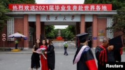 资料照:上海复旦大学学生在校门拍摄毕业照。(2021年6月25日)